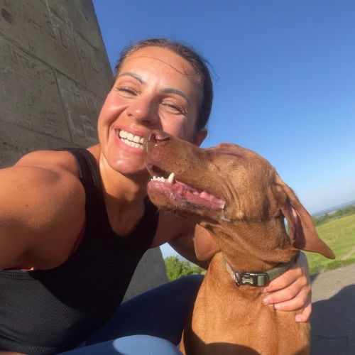 A woman smiles whilst cuddling her dog